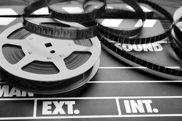 Movie clapper and film reel on table, closeup