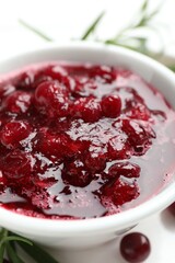 Tasty cranberry sauce in bowl on table, closeup
