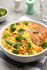Tasty rice with vegetables and chicken on table, closeup
