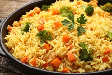 Tasty rice with vegetables in baking dish on table, closeup