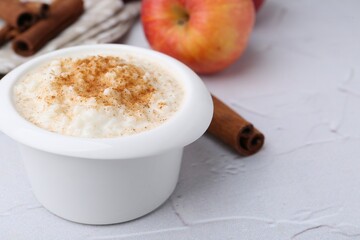 Delicious rice pudding with cinnamon and apple on white textured table, closeup. Space for text
