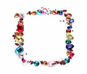 Frame of different shiny gemstones on white background, flat lay. Space for text