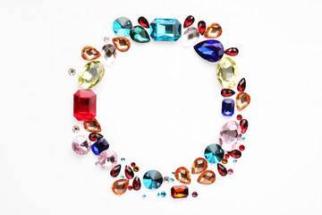 Frame of different shiny gemstones on white background, flat lay. Space for text