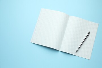 Open copybook and pen on light blue background, top view. Space for text