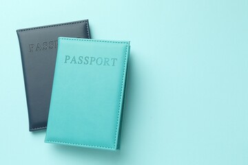 Passports in color covers on light blue background, top view. Space for text