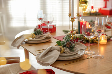 Christmas celebration. Festive table setting with dishware, glasses and decor in room