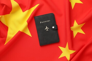 Passport in black cover on flag of China, top view