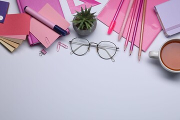 Designer's workplace with stationery, color palettes and cup of tea on grey table, flat lay. Space...