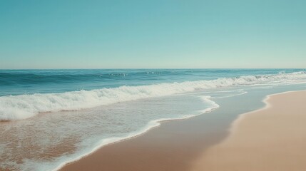 Fototapeta premium ocean waves gently lap against a serene beach, with soft golden sand and a clear blue sky, creating a tranquil natural setting that captures the essence of summertime relaxation and beauty