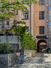 Helsinki alley with lone bike parked in bike rack among lush greenery and arched entryways.
