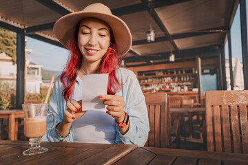 Happy tourist woman is checking bill, paying in cafe, after breakfast or lunch