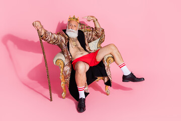 Full size photo of narcissistic king sit throne point finger gold crown isolated on pink color background