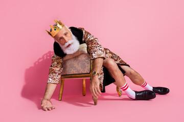 Photo of eccentric funky man king wear costume feel bad unwell after halloween party lying on chair over pink color background