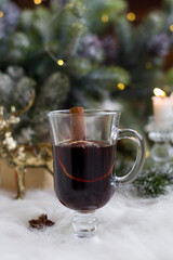 Winter hot drink mulled wine on the background of a Christmas tree with lights. New Year's decor, holiday