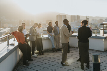 A diverse team of business colleagues standing on a rooftop balcony, engaged in brainstorming...