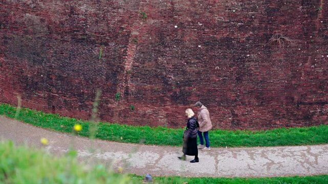 Persone a passeggio ai piedi delle mura di Lucca