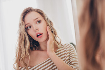 Young woman with blond hair in striped pullover resting indoors, enjoying a relaxed weekend at home