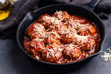Beef meatballs with tomato sauce and parmesan cheese on gray background, close up