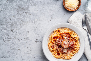 Spaghetti with meatballs, tomato sauce and parmesan on gray background