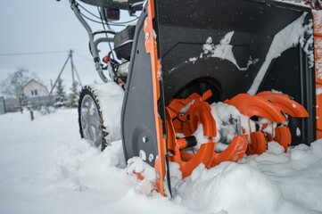 Close up photo of an orange petrol snow blower for private use. No recognizable parts or brands. In...