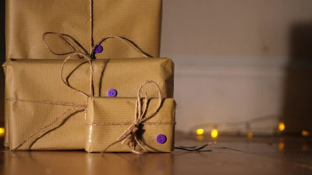 Gift wrapped in brown paper and string with Christmas lights bokeh background