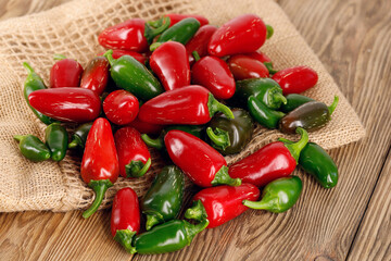 A freshly harvested pile of green and red jalapeno peppers on a wooden table, top view of hot chili peppers ready to be prepared