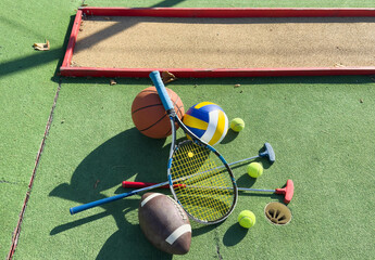 A variety of sports equipment including an american football, a soccer ball, a tennis racket, a...