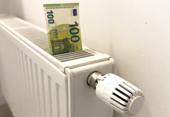 New thermostat with cash on a radiator heating at home. Expensive heating costs symbolic image.