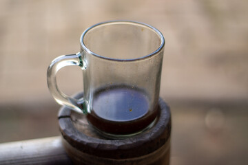 A cup of warm black coffee on a wooden table with a blurry background.
