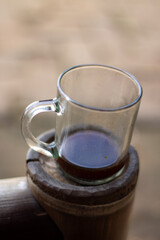 A cup of warm black coffee on a wooden table with a blurry background.
