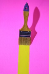 creatively arranged paint brushed on a pink background with yellow lines