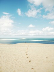 Footprints on the dune made by the footsteps of a girl walking towards the coast with the sea and...