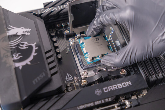 Poznan, Poland - November 25, 2024: AMD RYZEN 7 9800X3D CPU being carefully installed onto a carbon motherboard, demonstrating proper pc building and precision assembly