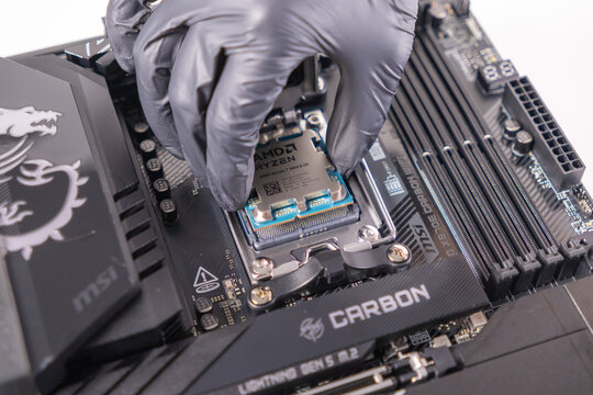 Poznan, Poland - November 25, 2024: hand installing an AMD RYZEN 7 9800X3D CPU into a MSI MEG X870E CARBON WIFI motherboard, emphasizing precision and technology