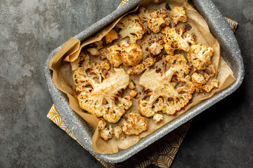 Oven Roasted Cauliflower with spices and oil, hard cheese Vegetable food on a dark grey background.