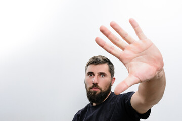 A man with a beard extends his hand towards the camera against a plain white background, creating a sense of stopping or blocking.