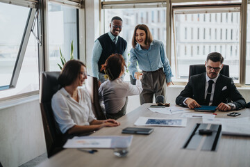 A diverse group of business people engaged in a meeting inside a modern office setting, discussing work and collaborating effectively around a conference table.