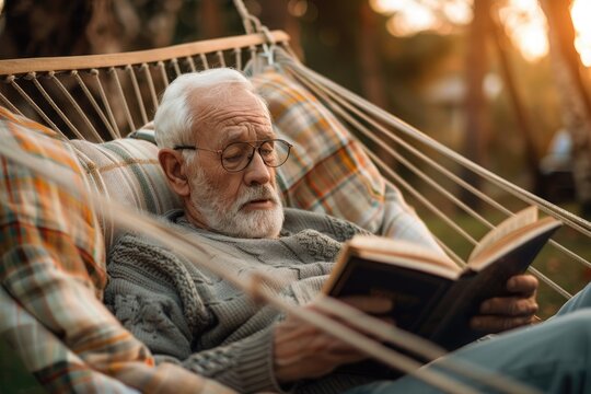 Elderly man lying on a hammock outdoors, reading a poetry book during sunset