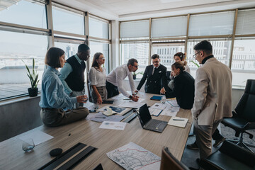 A multicultural group of business people collaborate in a modern office setting. They are engaged...