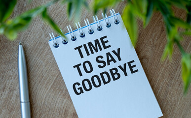 A pen sits on a notebook that says Time to Say Goodbye. The notebook is open to a blank page.