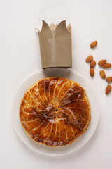 French king's cake or galette des rois with a golden crown placed on it and presented on a white plate and background, top vertical view, copy space