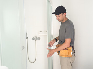 Plumber installing a shower cabin in bathroom