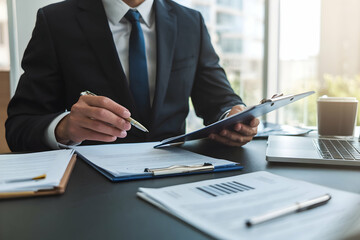 Man in suit taking notes at desk, office setting with natural light