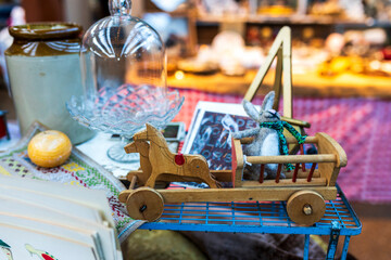A wooden cart harnessed with horses featuring a felt rabbit on display at a flea market with...