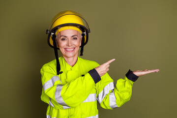 Confident senior female professional in yellow protective gear pointing enthusiastically, exemplifying expertise
