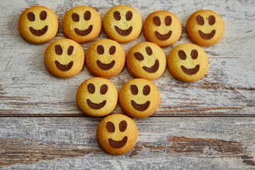 Naklejka premium Emoji smiley cookies arranged in a triangle shape on a wooden table in close-up, good mood, cheerful holidays, good family atmosphere, happiness and joy.