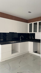Modern kitchen interior with sleek white cabinets, black marble backsplash, and minimalist design. Elegant countertops and spacious storage offer functionality and contemporary style.