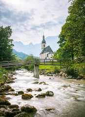 Schöne Berg Kirche in Deutschland Alpen. Panorama Sicht auf Feld, Gebirge und Wiese. Idylle wandern durch Wald und Natur. 
Beautiful mountain road in Germany alps. Panorama view field and meadow. 