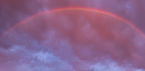 Rainbow appearing on cloudy sky at sunset