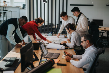 A group of diverse coworkers collaborates on a project in a modern office setting. The team is engaged in brainstorming and problem-solving, showcasing teamwork and communication.